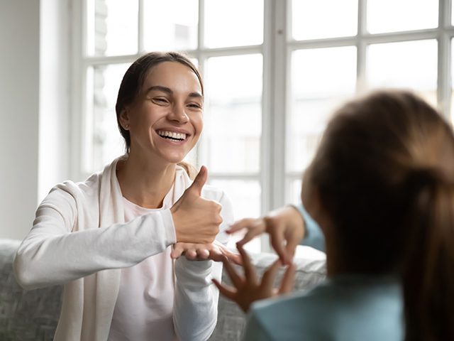 A woman giving thumbs up to another person.